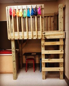 there is a loft bed made out of pallet wood and has colorful umbrellas on it