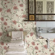 a sink and mirror in a small room with floral wallpaper on the walls behind it