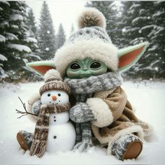 a baby yoda and snowman sitting in the snow