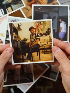 a person holding up a polaroid in front of a bunch of pictures