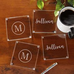 four acrylic coasters with the names of three different people on them next to a cup of coffee