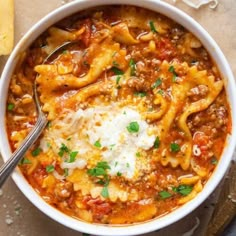 a white bowl filled with pasta and meat topped with parmesan cheese on top