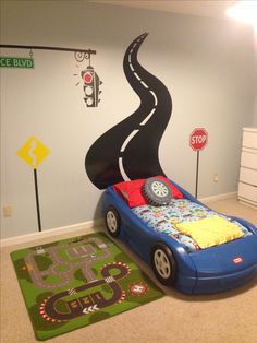 a child's bedroom with a car bed and rug