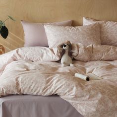 a stuffed animal sitting on top of a bed covered in pink comforters and pillows