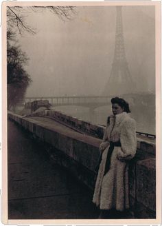 an old photo of a woman in front of the eiffel tower, paris