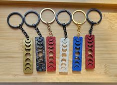 four different colored metal key chains on a wooden surface, with one in the middle