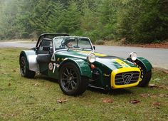 a green and yellow sports car parked on the side of a road next to trees