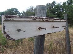 an old wooden sign with rusted paint on it in the middle of a field