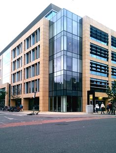 an office building with many windows and people walking on the sidewalk