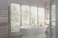 a white bath tub sitting in a bathroom next to a walk in shower and window