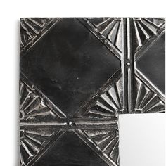 a black and white square tile with geometric designs on it's side, next to a mirror