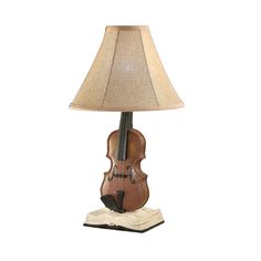 a lamp that has a violin on it and a book underneath the lamp is an open book