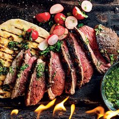 steaks and vegetables on a grill with fire