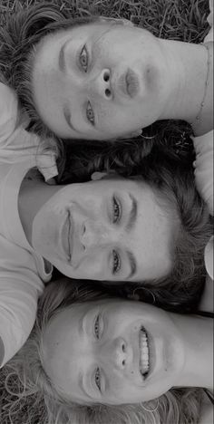 three people are laying on the grass and posing for a photo with their heads together