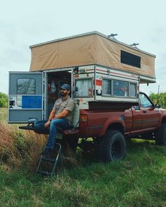 a man sitting in the back of a truck with a camper attached to it