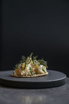 a black plate topped with food on top of a gray countertop next to a bottle of wine