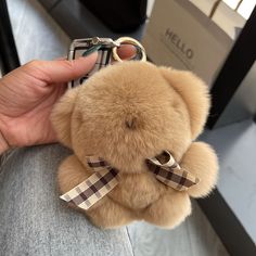 a person holding a brown teddy bear with a bow tie on it's neck