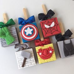 decorated cookies are arranged in the shape of superheros and spider - man blocks with toothpicks sticking out of them