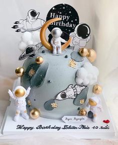 a birthday cake with an astronaut theme on it's top and gold decorations around the base