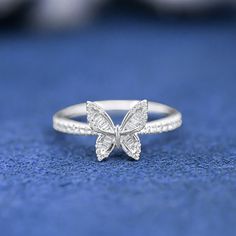 a white gold butterfly ring on a blue surface