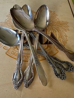 spoons and forks are arranged in a circle on a tablecloth with an ornate design