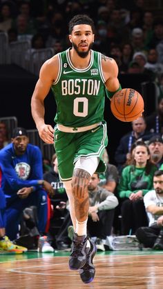 boston basketball player dribbling the ball down the court while fans watch from the stands