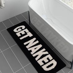 a bath tub sitting next to a black and white rug with the word gentleman on it