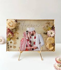 a wedding photo frame with flowers around it and a bride and groom holding each other