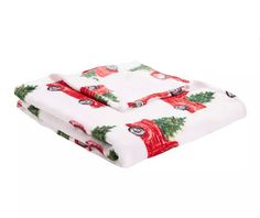 a white blanket with red and green christmas decorations on it's edges, rolled up