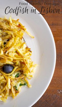 a white plate topped with food on top of a wooden table next to a fork