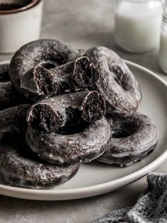 chocolate donuts on a plate next to a glass of milk