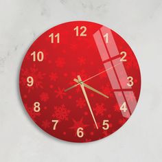 a red clock with snowflakes and numbers on the face is hanging on a wall