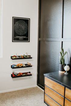 a black and white photo hanging on the wall next to a wooden dresser with three shelves