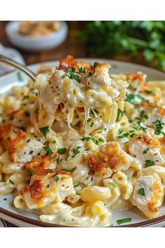 a white plate topped with pasta covered in chicken and parmesan cheese, on top of a wooden table