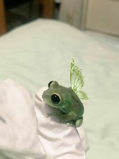 a green frog sitting on top of a white towel