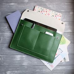 a green leather wallet sitting on top of some papers