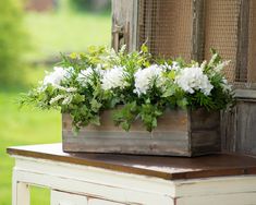 a wooden box with white flowers in it