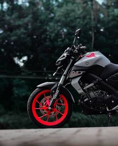 a motorcycle with red rims parked in front of some trees