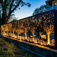 an illuminated fence with deer and trees on it