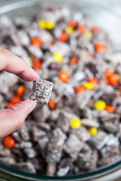 a hand holding a candy bar in front of a bowl full of muddy dog treats