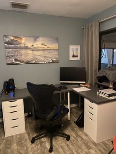 an office area with desk, chair and large painting on the wall in front of it