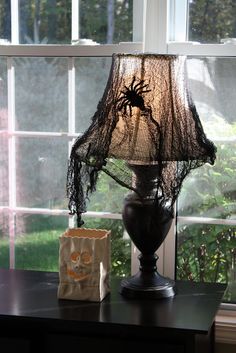 a spider lamp sitting on top of a wooden table next to a bag and window