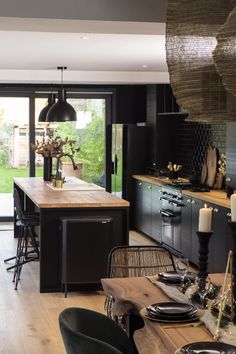 an open kitchen and dining room area with wooden flooring, black cabinets and counter tops