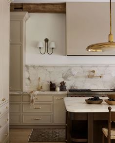 a kitchen with marble counter tops and gold accents on the cabinets, along with two hanging lights