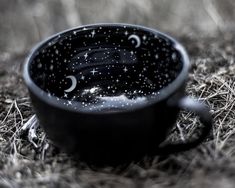 a black cup sitting on top of a grass covered ground with stars and crescents