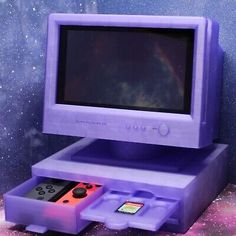 an old computer with a game controller in front of the screen and space behind it