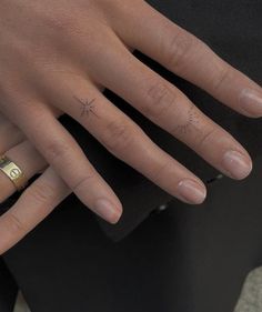 a woman's hand with a small star tattoo on her left ring and the other half of her finger