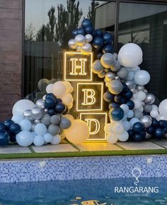 balloons are arranged around the letters that spell out happy birthday in front of a swimming pool