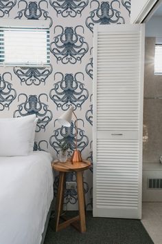 a bedroom with an octopus wallpaper and white bedding, next to a door