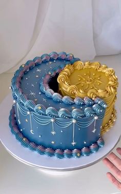 there is a blue and gold cake with stars on the top, sitting on a white plate